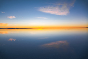 Sunrise on Salar de Uyuni in Bolivia covered with water, salt flat desert and sky reflections