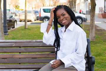 Close up portrait of a beautiful young african american woman with pigtails hairstyle in a business suit and white oversized blouse walks the street