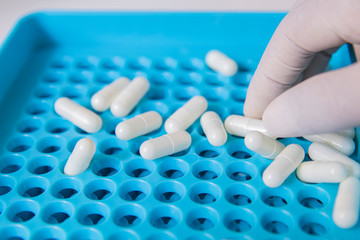 Hole of filling blue machines on white background for medicine fill have capsules drop down on surface. Concept medicine and production . concept healthcare. Pharmaceutical lab. anti-virus concept.