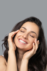 Beautiful dark-haired girl doing face yoga and closing her eyes