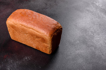 Fresh baked brown bread on a brown concrete background