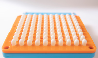 Naklejka premium White pill capsules are on hole of orange filling machines in hand
