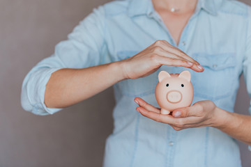 female hands protect pink piggy bank, copy space. Concept of saving money or savings