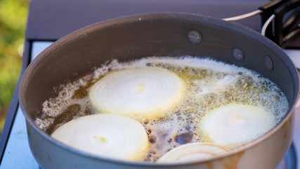 Sliced onions frying with butter in hot oil pan