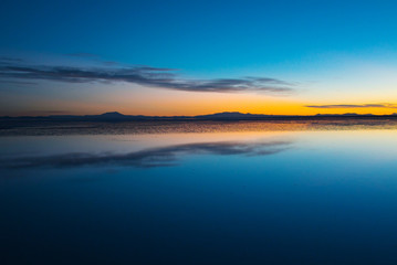 Sunrise on Salar de Uyuni in Bolivia covered with water, salt flat desert and sky reflections