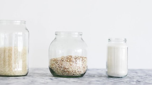 non-perishable pantry ingredients, glass jars with oats flour and rice and camera panning horizontally from eye-level perspective