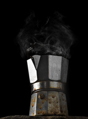 Italian coffee maker isolated on black background. Coffee Pot close up. Steam from brewed coffee rises above the coffee maker.