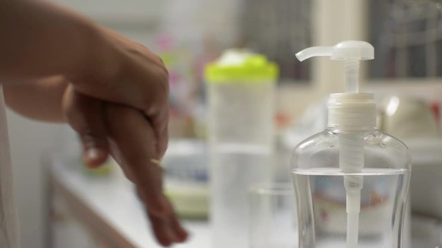 Woman cleaning her hands with alcohol gel during COVID-19 outbreak situation. Woman using hand sanitizing gel to prevent spreading virus before drinking water. Coronavirus protection. 