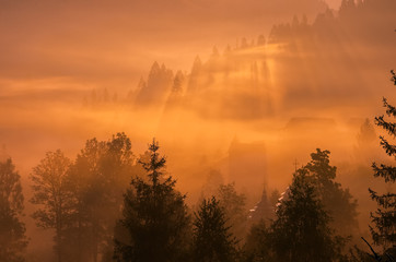 Picturesque fairy foggy sunrise over the village in mountains.