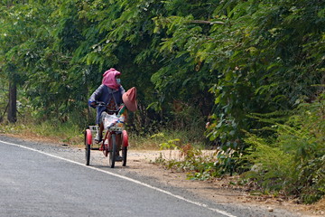 Obraz premium Old woman riding a tricycle 