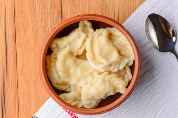 Traditional Ukrainian meat dumplings. Russian boiled pelmeni served in a bowl with sauce on white tablecloth