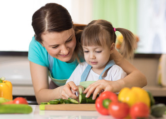 Toddler girl cooking with her mother in kitchen