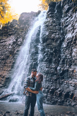 couple in front of waterfall autumn season