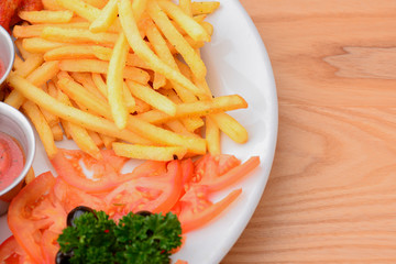 Close up gourmet main dish for dinner with crispy fried chicken, french fries and veggies on white plate.