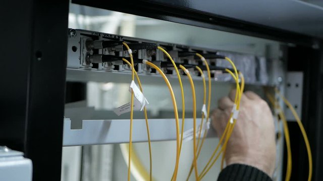 Network engineer in server room works with optical patchcord and optical module.