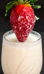 Fresh strawberries with milk on a black background
