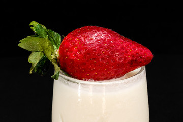 Fresh strawberries with milk on a black background