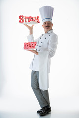 The cook keeps the plates labeled steak and beef plates in his hands