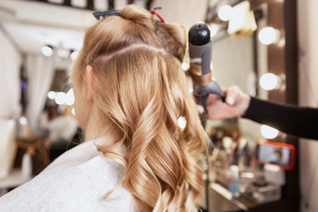 Blonde girl in a beauty salon doing a hairstyle. Close-up.