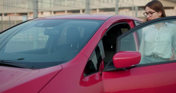 Attractive female using modern technology to unlock car doors. Woman pening door and getting in car. A girl opens the car and sits inside
