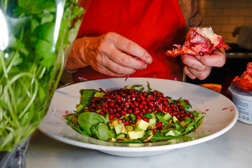 Stockholm, Sweden  A young woman prepares a salad with pomegranate and avocado