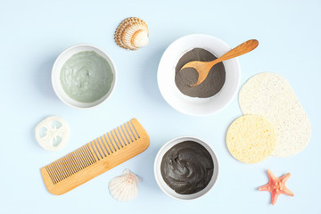 SPA natural organic beauty products for face skin care and treatment. Top view. Cosmetic clay mask and powder in bowls, luffa sponge, hair comb on pastel blue background.