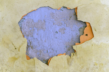 crumbling plaster on a yellow wall with a blue and orange base