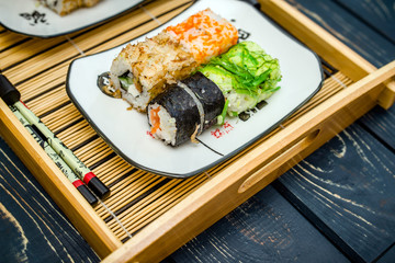 Several sushi on a white plate standing on a brown background