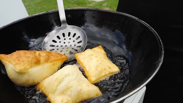Fried chebureks in oil in black pans top view