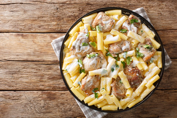 Italian dinner of pasta Tortiglioni with chicken in cheese cream sauce with herbs close up in a dish. Horizontal top view