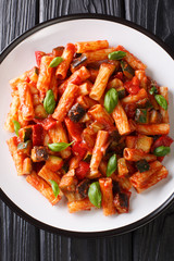 Vegetarian Tortiglioni pasta with vegetables and basil in tomato sauce close-up in a plate. Vertical top view