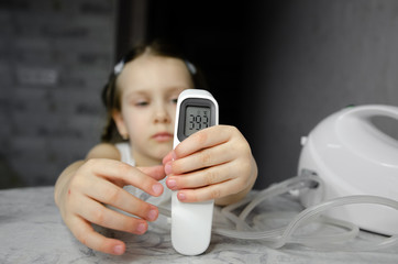  digital infrared thermometer with a high temperature lies on the table against the background of a...