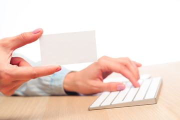female hands type on a modern wireless keyboard and show a business card with your text place - Image