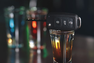 Drinking and driving concept. Car key on a wooden table, pub background