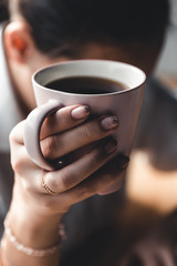 Woman in the morning drinks coffee and reads old book in a white shirt. Education, drink. manicure