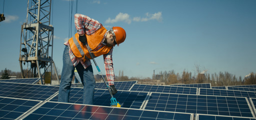 Technician cleaning solar panels on flat roof