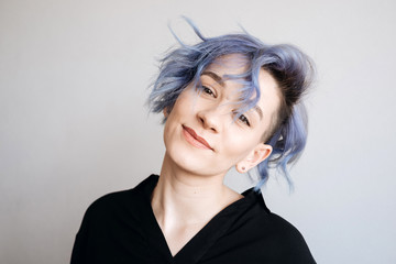 A beautiful girl with blue hair is smiling.