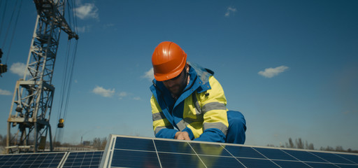 Technician installing solar panel and looking at camera