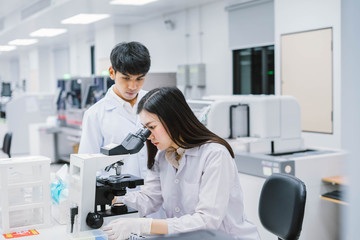 Two  medical  scientist working in Medical laboratory , young female scientist looking at microscope. select focus in young  female scientist