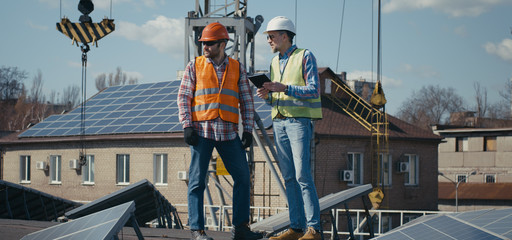 Naklejka premium Engineer and technician discussing between solar panels