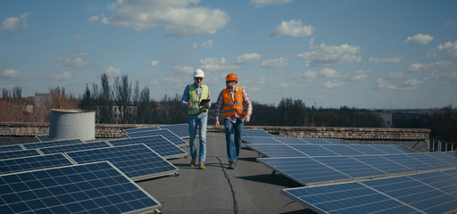 Engineer and technician discussing between solar panels - obrazy, fototapety, plakaty