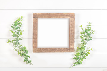 Rough wood square frame on a white background with green branches