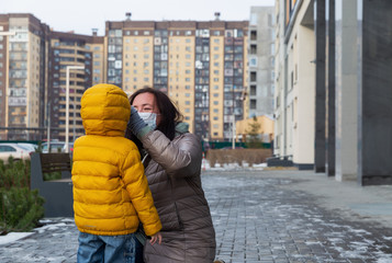 A mother puts protective mask on herself and on her little son