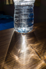 Refraction of sunlight afte passing through a water in a plastic bottle, with shallow depth of field