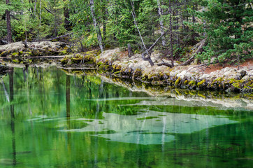 Small forest lake with greenish water in the autumn forest, lava lake