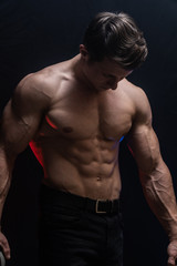 Fototapeta premium Muscular man showing muscles isolated on the black background with colored smoke. Concept of healthy lifestyle 