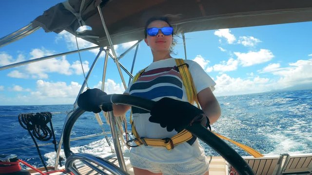 Girl holds a helm while driving yacht.