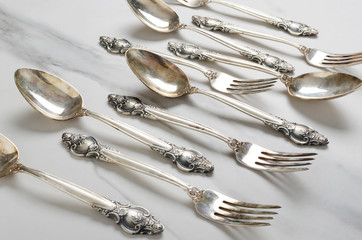 Closeup of vintage spoons and fork with decorative handles on the white table