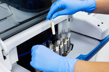 close-up of biochemist arms in blue gloves analyzing test tubes with medical samples at lab