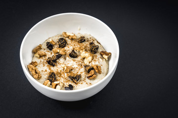 Oatmeal recipe with walnuts, prunes, cinnamon and sugar with black background